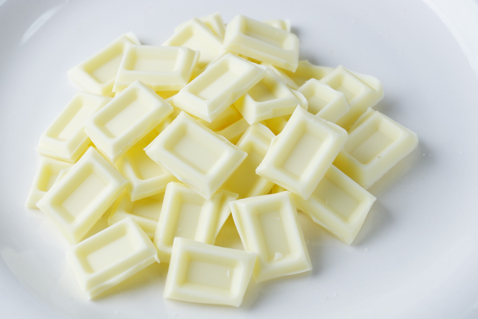 Кусочки белого шоколада. Белый шоколад. Белая шоколадка. Шоколад на белом фоне.