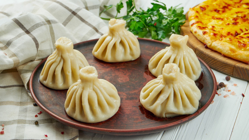 appetitnye-domasnie-hinkali-s-razlicnymi-nacinkami-fars-syr-ovosi-ili-spinat-v-koricnevoi-tarelke-na-derevannom-fone-tradicionnaa-gruzinskaa-kuhna-gruzinskie-pel-meni