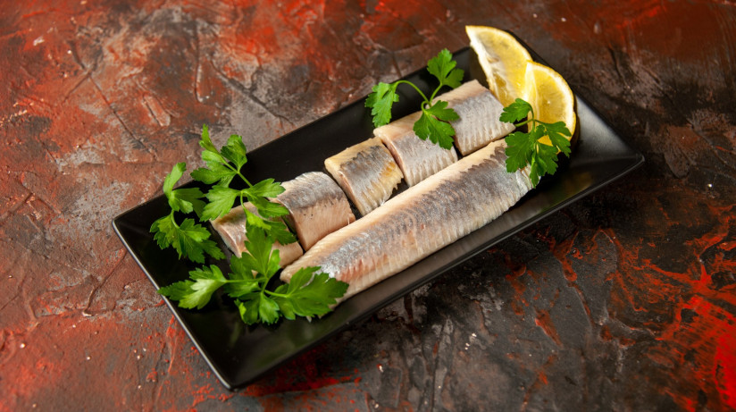 vid-speredi-svezei-narezannoi-ryby-s-zelen-u-i-kusockami-limona-vnutri-cernoi-skovorody-na-temnyh-masnyh-zakuskah