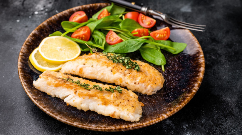 obzarennye-file-treski-beloe-maso-ryby-na-tarelke-s-salatom-cernyi-fon-vid-sverhu