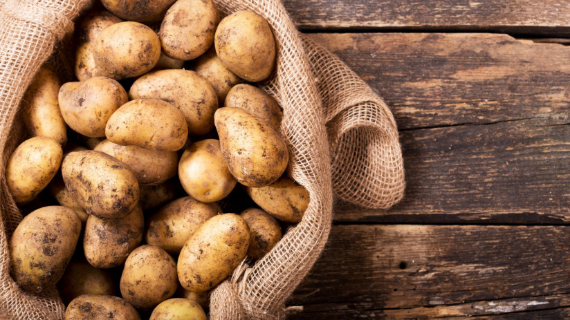 svezii-kartofel-v-meske-na-derevannom-stole-vid-sverhu