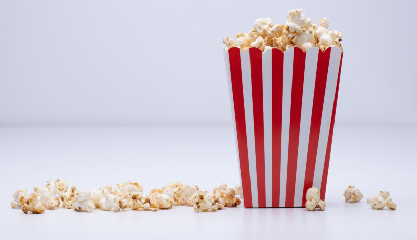 1 paper-cup-popcorn-some-popcorn-scattered-around-white-surface (1)